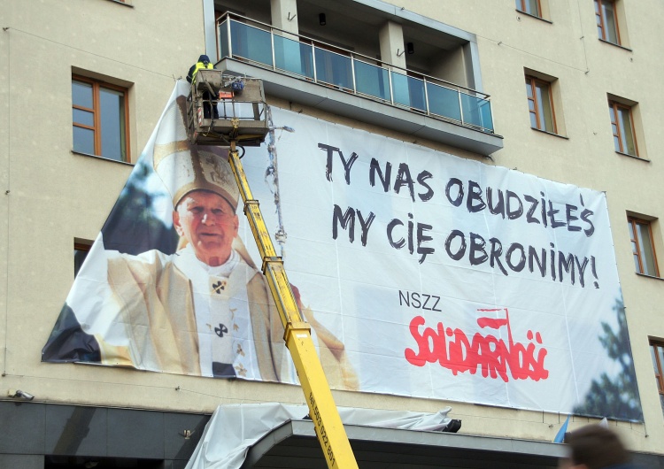 grafika. P. Machnica Banner z wizerunkiem św. Jana Pawła II zawisł na budynku Solidarności i Bazylice św. Brygidy w Gdańsku